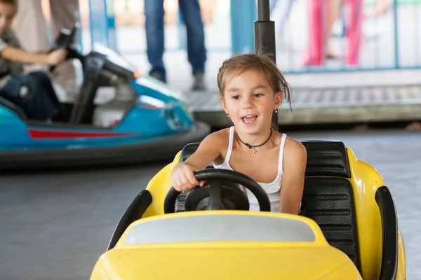 Счастливый ребенок ездит на электромобиле по парку — стоковое фото
