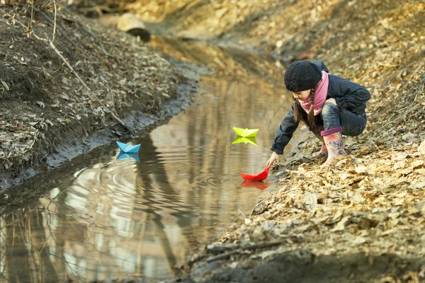 Κορίτσι στην όχθη του ποταμού παίζει χάρτινο καραβάκι — Φωτογραφία Αρχείου