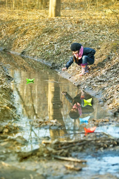 Κορίτσι στην όχθη του ποταμού παίζει χάρτινο καραβάκι — Φωτογραφία Αρχείου