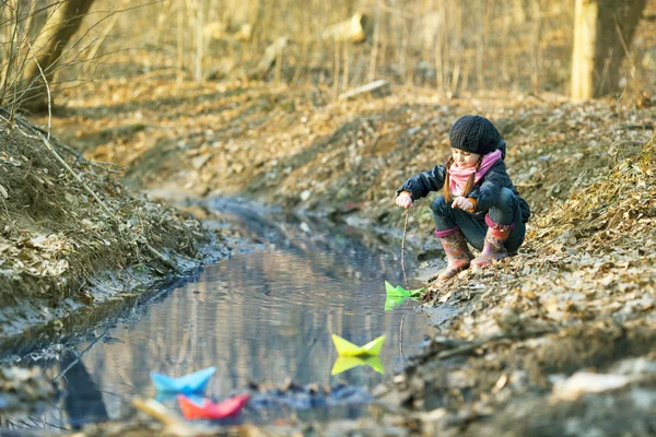 Mädchen am Flussufer spielt Papierboot — Stockfoto