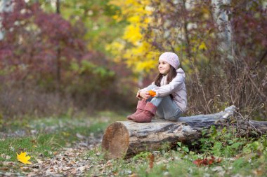 Ormanın içinde bir günlük üzerinde oturan kız