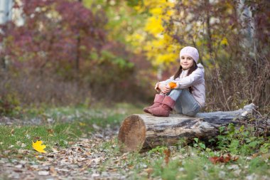 Ormanın içinde bir günlük üzerinde oturan kız