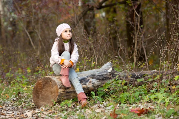 Dívka sedící na kládu v lese — Stock fotografie