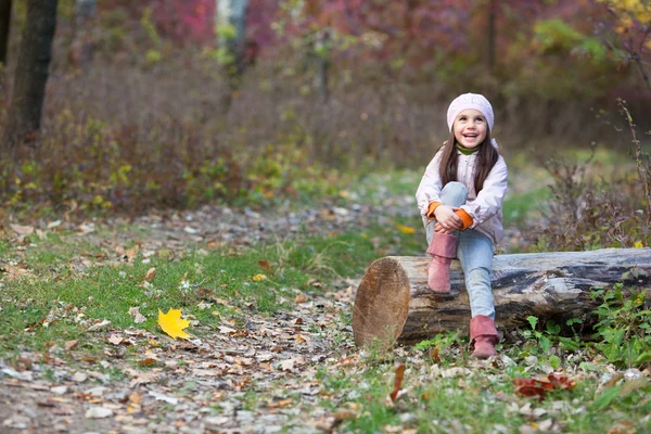 Fille assise sur une bûche dans les bois — Photo