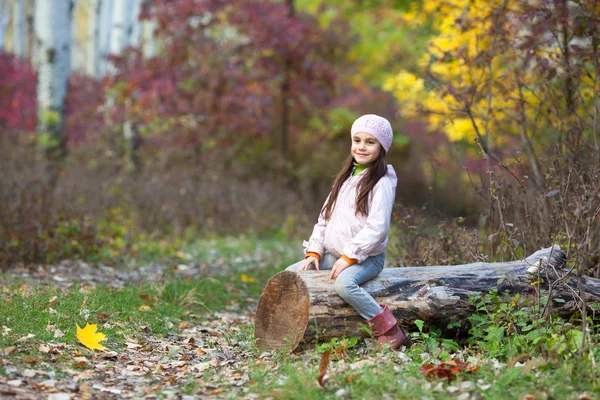 Chica sentada en un tronco en el bosque — Foto de Stock