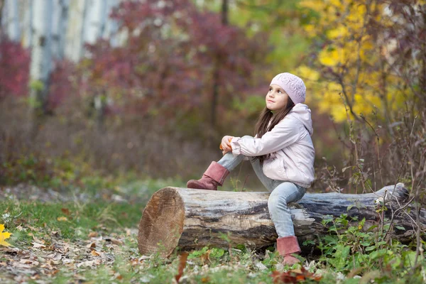 Menina sentado em um log na floresta — Fotografia de Stock