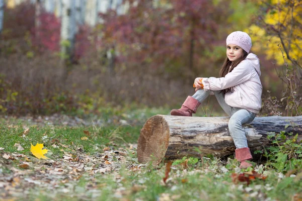 Fille assise sur une bûche dans les bois — Photo