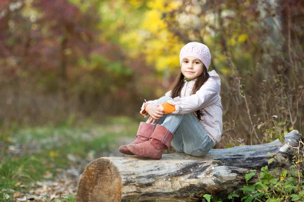 Menina sentado em um log na floresta — Fotografia de Stock