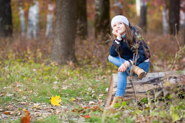 Meisje, zittend op een logboek in het bos — Stockfoto