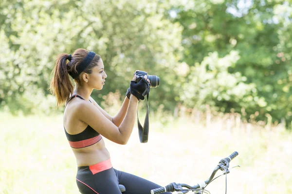 Atletische vrouw met fiets nemen van foto's, buiten. — Stockfoto