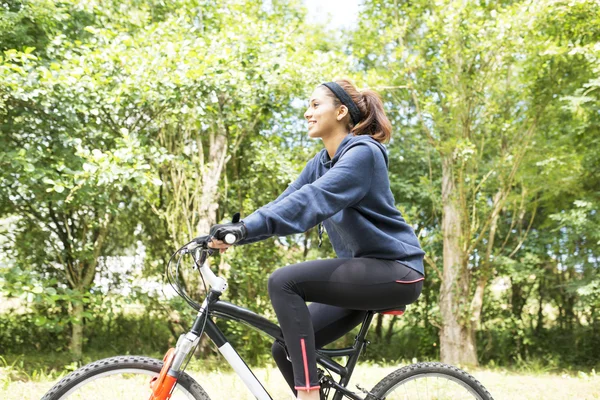 Lächelnd schöne junge Frau, die mit dem Fahrrad trainiert, im Freien. — Stockfoto