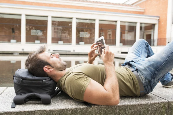 Homem casual relaxante e olhando tablet computador na rua, conceito de estilo de vida moderno . — Fotografia de Stock