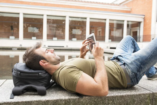 Casual adam rahatlatıcı ve sokak, modern yaşam tarzı kavramında tablet bilgisayar arıyorum.