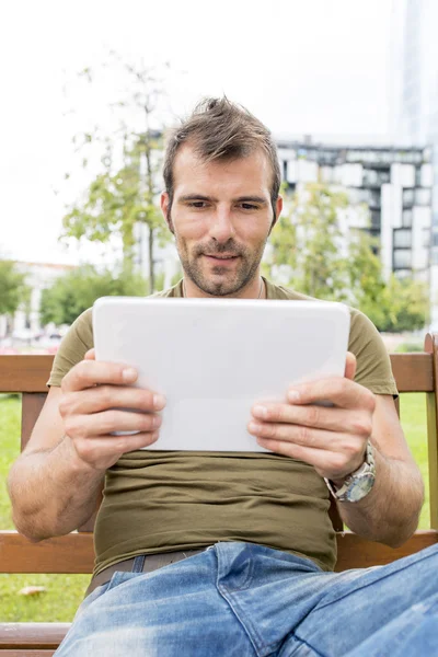 Retrato del hombre mirando mensaje en la tableta, al aire libre . — Foto de Stock