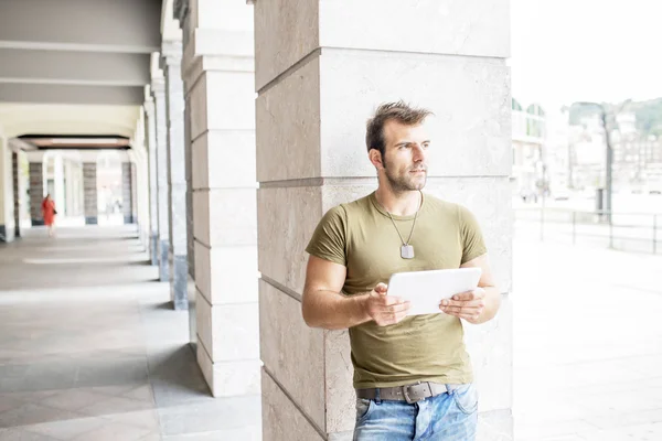 Lässiger moderner Mann mit Tablet-Computer auf der Straße, der wegschaut. — Stockfoto