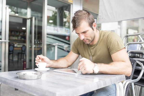 Adam içme kahve ve laptop tablet bilgisayar Teras restoranda.