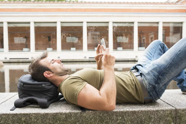 Man rust liggen in het park en laptop tablet pc, moderne leven concept. — Stockfoto
