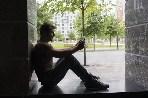 Backlight do homem com computador tablet sentado na rua . — Fotografia de Stock