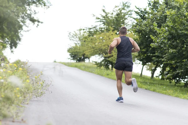 Hombre atlético corriendo cuesta arriba, al aire libre . —  Fotos de Stock