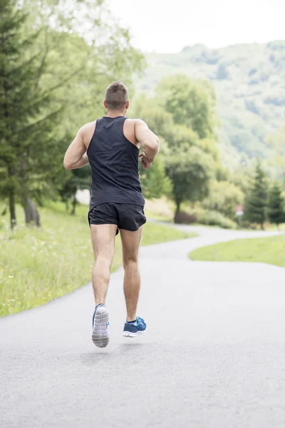 Starker, athletischer Mann, der die Straße hinunterläuft, Konzept eines gesunden Lebensstils. — Stockfoto