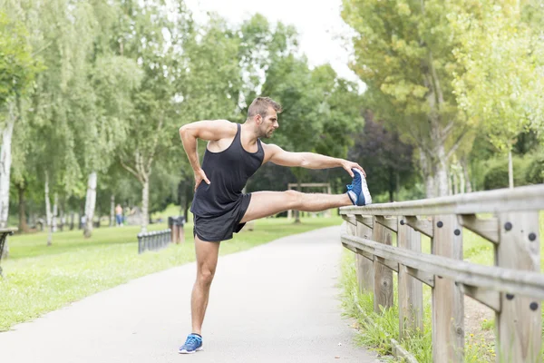 健康的なライフ スタイルのコンセプトを行使する前に行う運動の強い男を伸ばす. — ストック写真