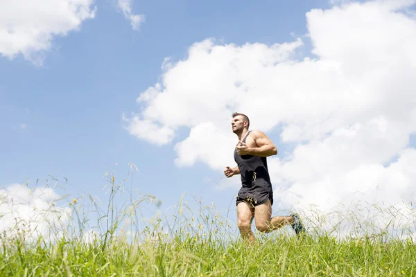 Starker athletischer Mann läuft auf dem Feld. — Stockfoto