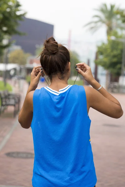 Mujer atleta hasta los auriculares antes de hacer ejercicio, al aire libre . —  Fotos de Stock