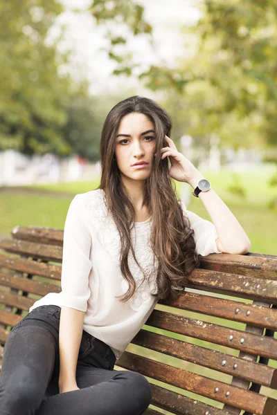 Schöne sinnliche Frau sitzt auf einer alten Sitzbank im Park. — Stockfoto