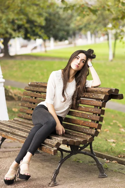 Pensive and elegant beautiful woman sitting on old bench. — Stock Photo, Image