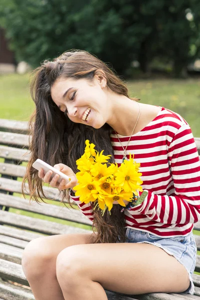 Smiling happiness woman with flowers looking message on mobile, feeling concept. — Stock Photo, Image