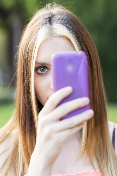 Portrait de closeau de belle femme regardant de behing téléphone intelligent et de prendre des photos . — Photo