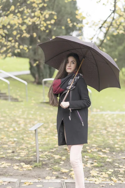 Schöne nachdenkliche Frau mit Regenschirm im Park. — Stockfoto