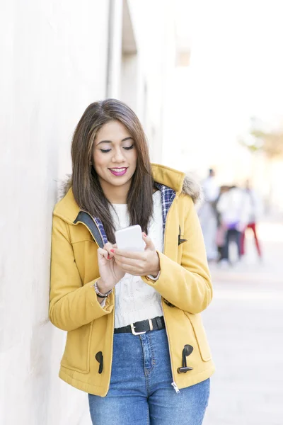 Sorrindo bela mulher latina usando telefone inteligente na rua . — Fotografia de Stock