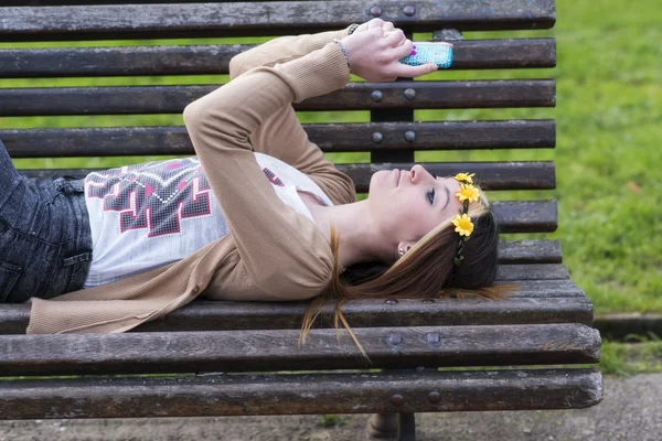 Felicità bella ragazza con smart phone sdraiato sulla panchina . — Foto Stock