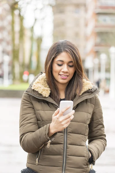 Uśmiechający się wyglądający wiadomość na inteligentny telefon na ulicy. — Zdjęcie stockowe