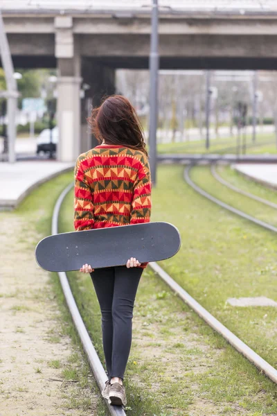 Junge Hipsterfrau läuft mit alten Schienen auf der Straße, Lifestylekonzept für Adoleszenz. — Stockfoto