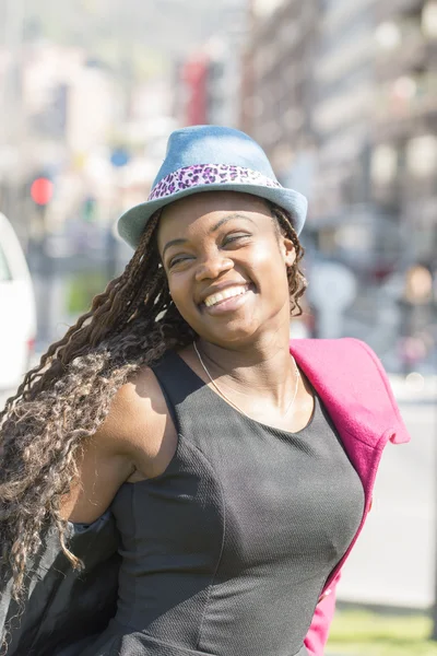 戴着帽子在街上的微笑美丽的非洲女人的画像. — 图库照片