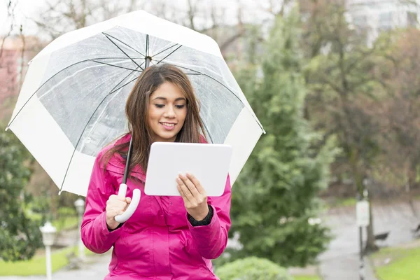 Happiness woman with umbrella and tablet computer in the park. — Stock Photo, Image