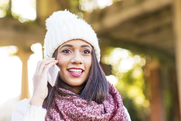 Portrait of woman with cap talking by smart phone, outdoor. — Stock Photo, Image