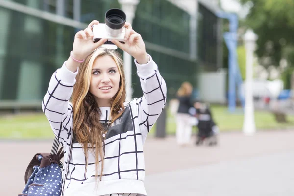 Mooie youn vrouw neemt foto's met de camera in de straat. — Stockfoto