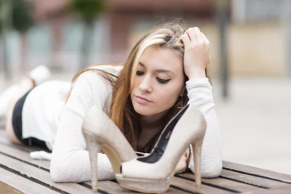 Beautiful elegance young woman lying on bench with heels. — Stock Photo, Image