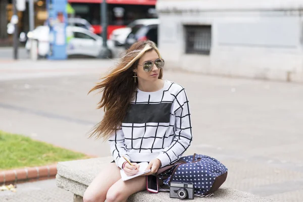 Hipster junge Frau unterwegs und macht sich Notizen auf der Straße. — Stockfoto