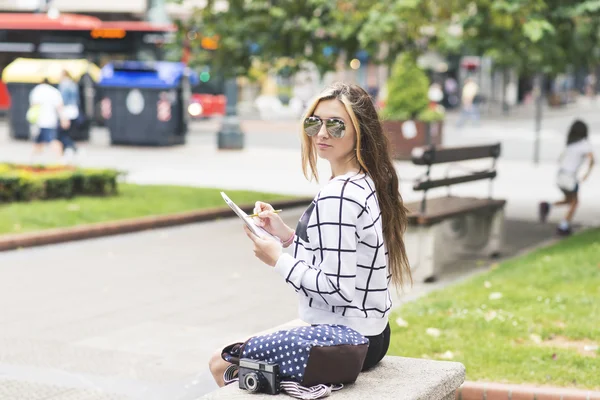 Hipster young woman traveling and taking notes in the street. — Stock Photo, Image