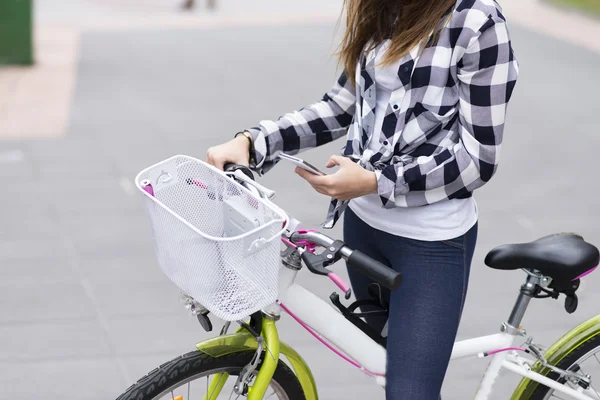 Händerna på flickan med cykel med hjälp av smart telefon, moderna livsstilskoncept. — Stockfoto