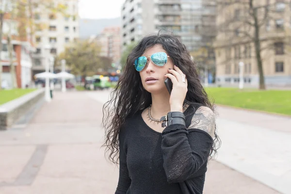 Mulher com óculos de sol falando por telefone na rua . — Fotografia de Stock