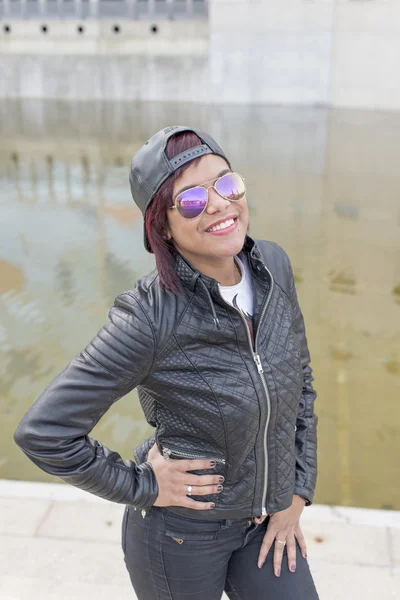 Retrato urbano de mulher latina de moda sorridente com óculos de sol e boné de beisebol . — Fotografia de Stock