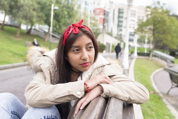 Jeune femme réfléchie assise sur un banc et regardant ailleurs . — Photo