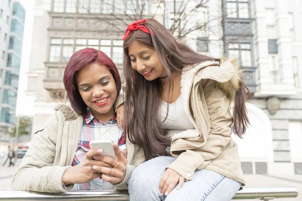 Two smiling woman friends sharing social media in a smart phone. — Stock Photo, Image