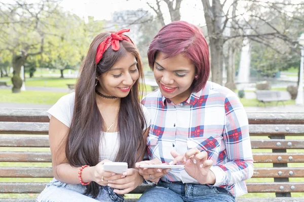 Two smiling woman friends sharing social media in a smart phone. — Stock Photo, Image