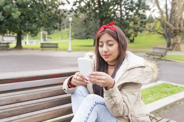 Femme assise sur le banc et regardant messahe son smartphone . — Photo